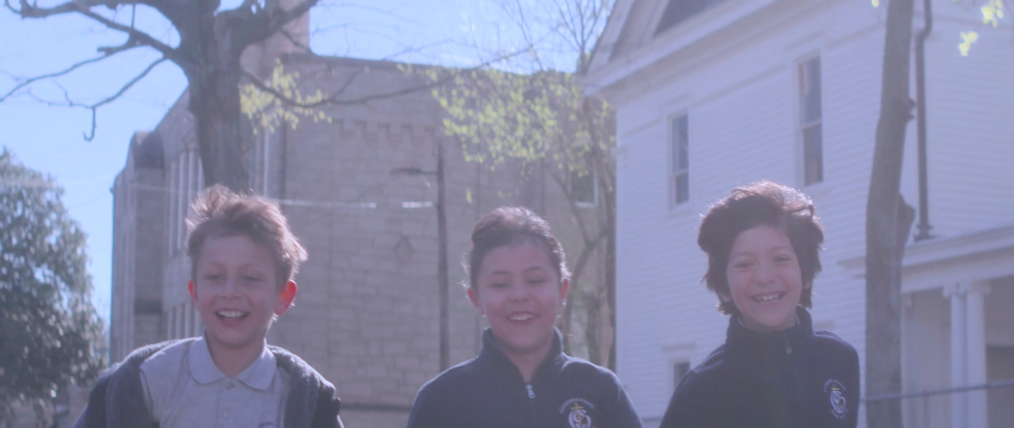 Students laughing together on the sidewalk outside school