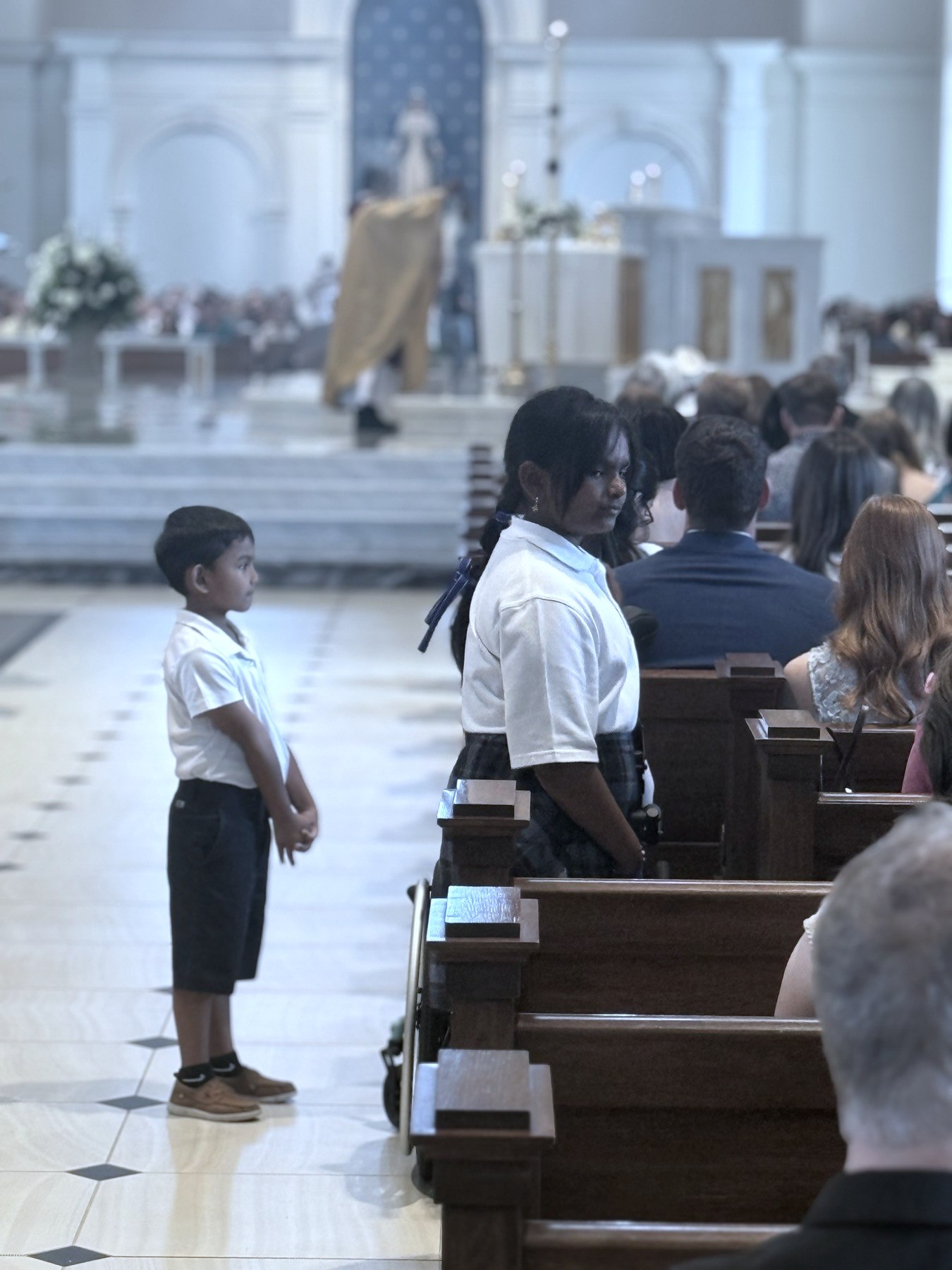 Students at Mass in the cathedral, the priest at the altar beyond